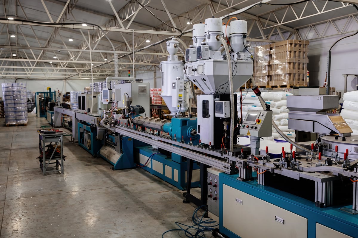 Wide view along a polymer extrusion production line, showing machinery layout and the surrounding facility