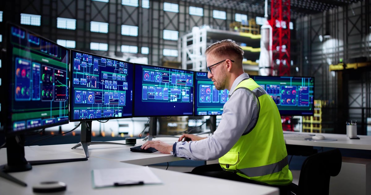 Engineer monitoring production data at a control station in a factory